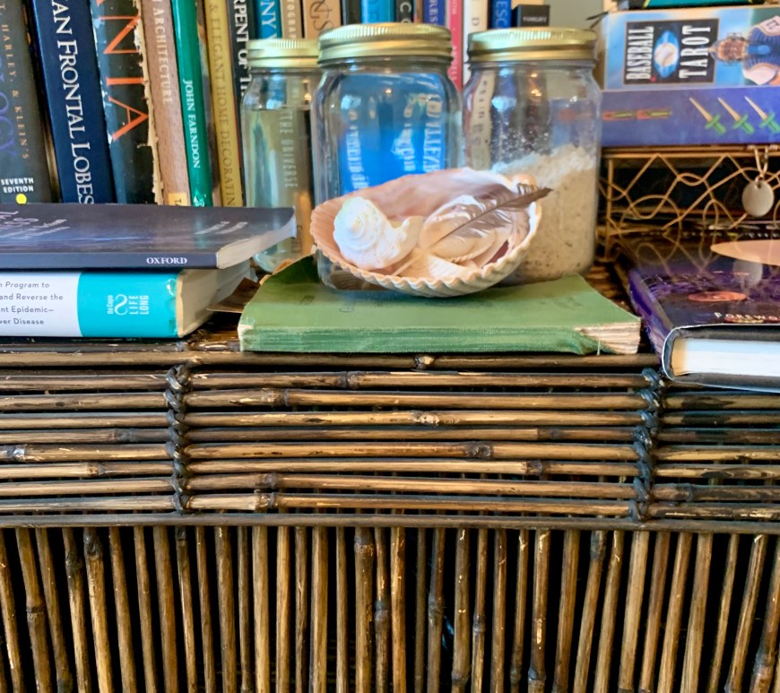 A bamboo chest holds bedding, plus books, shells, ocean water, and a metal wire box.