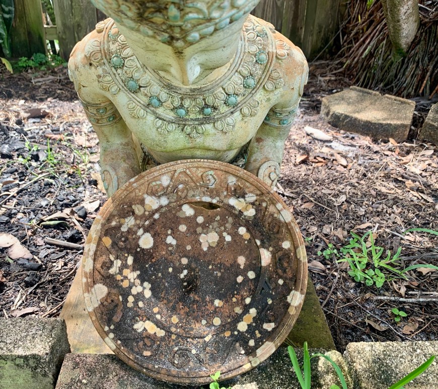 Kneeling Buddhist statue in garden.