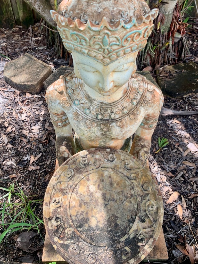 Kneeling Buddhist statue in garden.